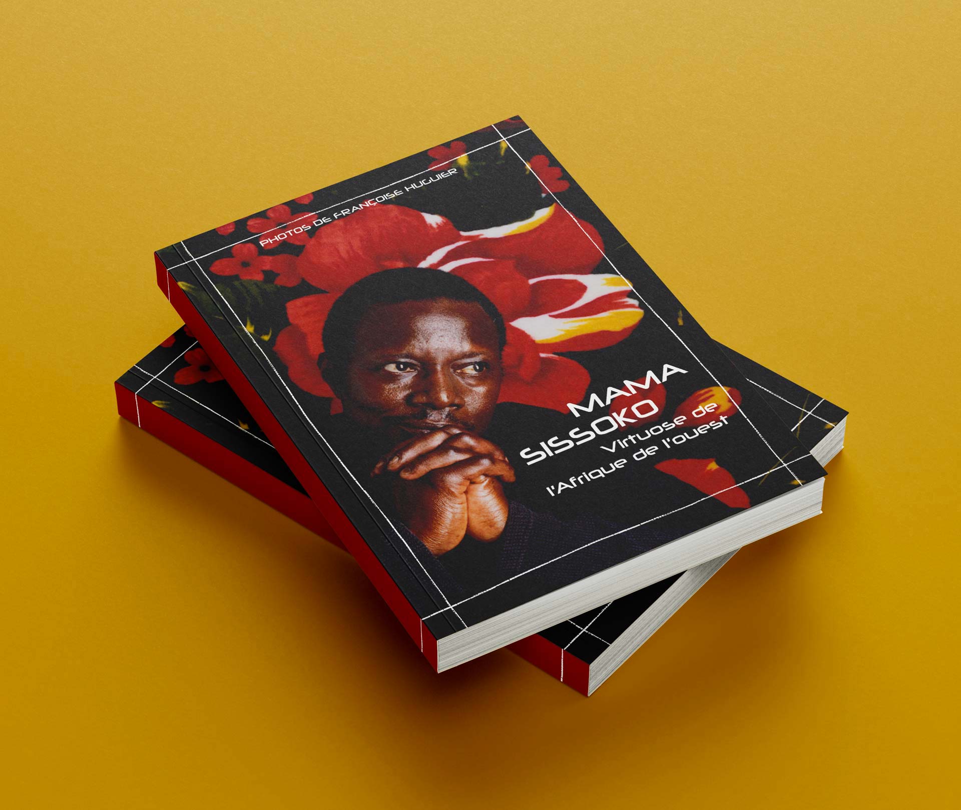 Deux livres brochés posés sur un fond jaune, montrant une couverture noire avec une grande fleur rouge en arrière-plan et un portrait au premier plan, accompagnée du titre imprimé ‘Mama Sissoko, Virtuose de l’Afrique de l’Ouest’.